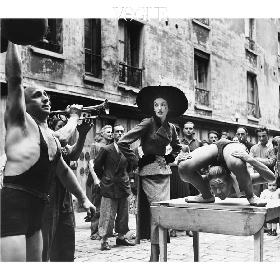 Elise Daniels with street performers, Le Marais, Paris, 1948. Suit by Balenciaga