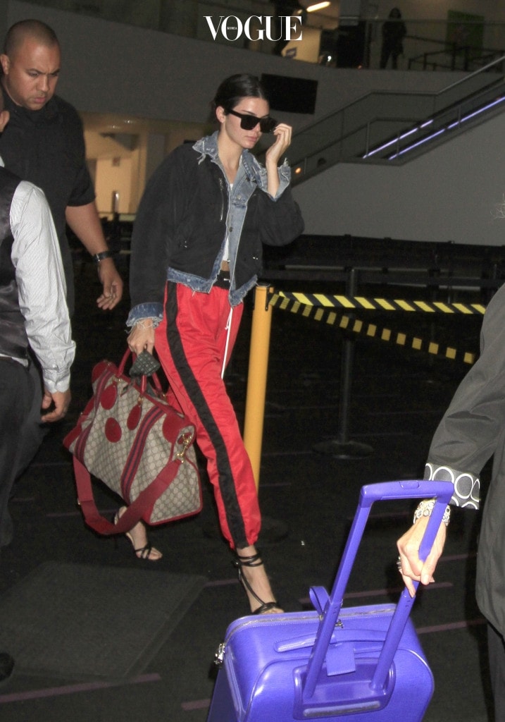 Kendall Jenner catches a flight out of town carrying a very expensive Gucci handbag, designer luggage with the name "KENNY" on it, red workout pants, heels and a crop top showing off her toned stomach.  The KUWTK star and supermodel was seen flying out of LAX with her burly bodyguard.  Kendall was seen getting going through TSA after she set off the alarm the first time and needing to take off her shoes.  Jenner who was wearing dark sunglasses had her hair in a bun needed to take her jacket off showing off her toned arms in a white tank top. Pictured: Kendall Jenner Ref: SPL1510212  310517   Picture by: Sharky/Polite Paparazzi/SPLASH Splash News and Pictures Los Angeles:310-821-2666 New York:212-619-2666 London:870-934-2666 photodesk@splashnews.com 