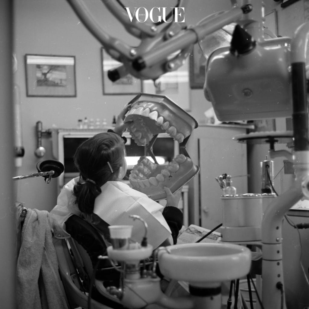 A young patient in the dentist's chair holding a giant model of a set of dentures which the dental hygienist uses to demonstrate proper brushing techniques. (Photo by Orlando/Getty Images)